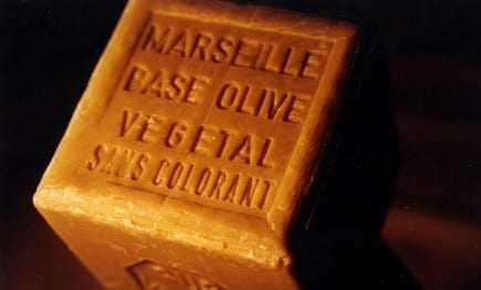 A rectangular bar of Marseille soap with embossed text indicating its olive oil base and natural ingredients. - Olive Oil Times