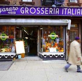 Storefront of Grosseria Italiana with a sign and display of flowers and produce. - Olive Oil Times