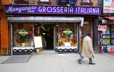Storefront of Grosseria Italiana with a sign and display of flowers and produce. - Olive Oil Times