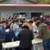 A large group of people gathered outdoors at an event, with some individuals serving food at tables. - Olive Oil Times