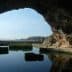 View of a cave opening with water reflecting the surrounding rock formations. - Olive Oil Times