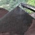 Conveyor belt transferring black soil to a pile in an outdoor setting. - Olive Oil Times