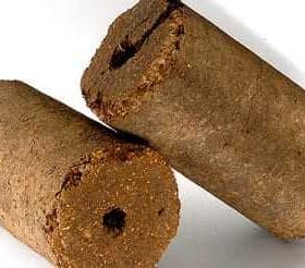 Two cylindrical olive oil briquettes with a textured surface and a hole in the center. - Olive Oil Times