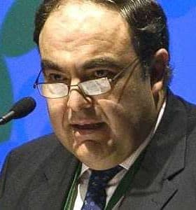 A man wearing glasses speaking at a podium during a conference or event. - Olive Oil Times