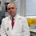 A man wearing a lab coat and a red tie sitting in a laboratory environment. - Olive Oil Times