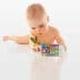 Infant exploring a colorful toy with numbers and letters while holding a small plant. - Olive Oil Times