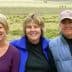 Three women standing together outdoors, smiling at the camera with a grassy background. - Olive Oil Times