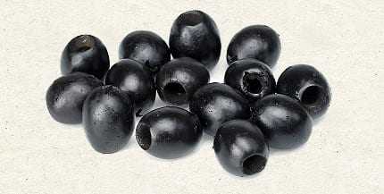 A group of black olives arranged on a light background, showcasing their oval shape and dark color. - Olive Oil Times