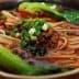 Bowl of Chinese noodle soup with green onions and bok choy in a rich broth. - Olive Oil Times