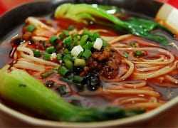 Bowl of Chinese noodle soup with green onions and bok choy in a rich broth. - Olive Oil Times
