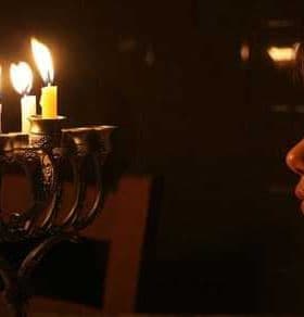 A child gazing at a menorah with lit candles during a celebration. - Olive Oil Times