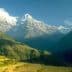 Snow-capped mountains in Nepal with clear blue sky and green hills in the foreground. - Olive Oil Times