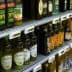 Multiple bottles of olive oil displayed on shelves in a grocery store. - Olive Oil Times