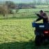 Individual on an ATV pouring material from a bucket while in a grassy field. - Olive Oil Times