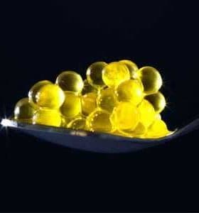 A spoon holding yellow caviar pearls arranged in a clustered formation. - Olive Oil Times
