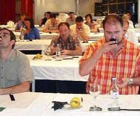 Participants at an olive oil tasting event seated at tables with glasses and bottles. - Olive Oil Times