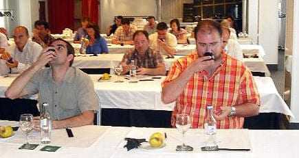 Participants at an olive oil tasting event seated at tables with glasses and bottles. - Olive Oil Times