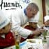 Chef demonstrating cooking techniques to children wearing chef hats at a table. - Olive Oil Times