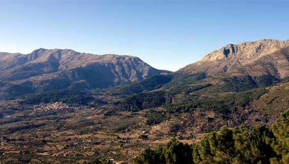 Panoramic view of Tietar Valley featuring mountains and greenery under a clear sky. - Olive Oil Times