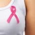 Close-up of a pink ribbon pinned on a white shirt worn by a person. - Olive Oil Times