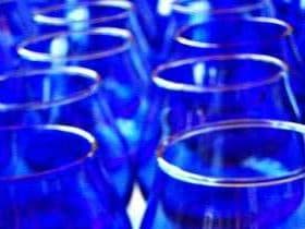 Row of blue tasting glasses arranged closely together, showcasing their transparent design. - Olive Oil Times