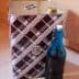 A square metal container with a patterned design next to a blue glass bottle. - Olive Oil Times