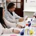 A group of individuals in lab coats engaged in a discussion around a table with various items and documents. - Olive Oil Times