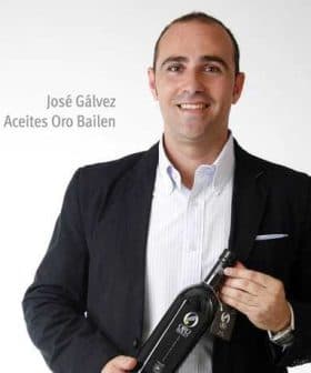José Gálvez holding a bottle of Oro Bailen olive oil while wearing a black blazer and white shirt. - Olive Oil Times