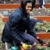 Woman wearing gloves and a jacket planting in a garden bed with vegetables. - Olive Oil Times