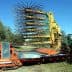 Olive harvesting machine with a large rake attachment and a tractor in a field. - Olive Oil Times