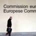 A person walking past the European Commission signage with the EU flag displayed on the wall. - Olive Oil Times