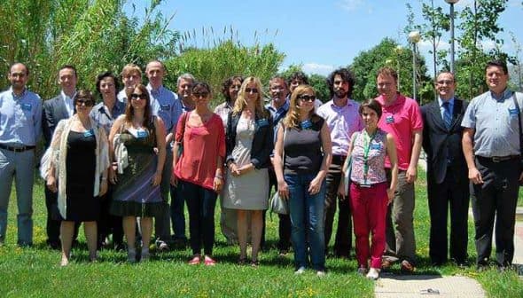 A group of diverse individuals posing together outdoors in a green area with trees and grass. - Olive Oil Times