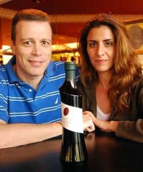 Two individuals, a man and a woman, posing with a bottle of olive oil in a restaurant setting. - Olive Oil Times