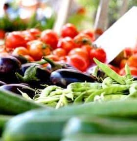 A selection of fresh vegetables including cucumbers, eggplants, and green beans displayed at a market. - Olive Oil Times
