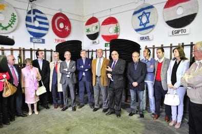A group of individuals standing in a meeting room with flags displayed on the wall behind them. - Olive Oil Times