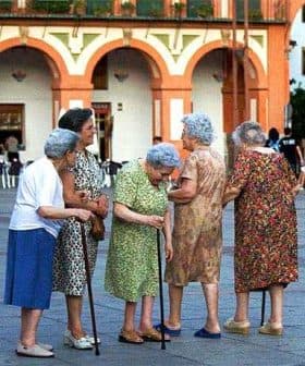 Group of elderly women gathered in a plaza in Córdoba, engaged in conversation. - Olive Oil Times