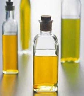 Four glass bottles containing different types of olive oil with cork stoppers. - Olive Oil Times