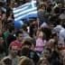 A large crowd of people with a young girl holding a Greek flag in a public gathering. - Olive Oil Times