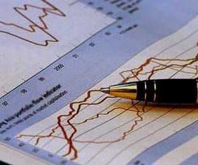 A pen resting on a sheet of paper with financial graphs and data trends. - Olive Oil Times