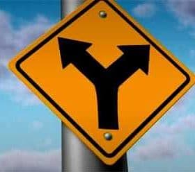 Yellow traffic sign indicating a Y-intersection with arrows pointing left and right. - Olive Oil Times