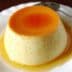 A smooth custard dessert topped with a layer of caramel sauce on a white plate. - Olive Oil Times