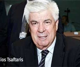 Athanassios Tsafaris seated at a table, wearing a black suit and tie, with a neutral expression. - Olive Oil Times