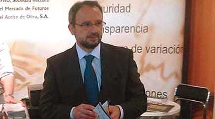 Man wearing glasses and a suit holding a document at a conference or event. - Olive Oil Times