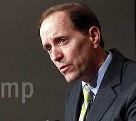 Man in a suit speaking during a press conference with a serious expression. - Olive Oil Times