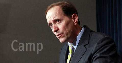 Man in a suit speaking during a press conference with a serious expression. - Olive Oil Times
