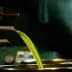 Green olive oil flowing from a spout into a metal container during the extraction process. - Olive Oil Times