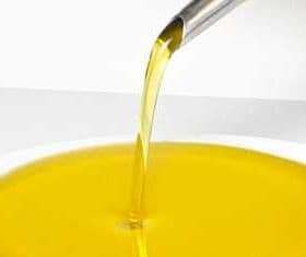 Stream of olive oil being poured from a spout into a white bowl. - Olive Oil Times