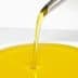 Stream of olive oil being poured from a spout into a white bowl. - Olive Oil Times