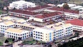 Aerial view of a campus featuring several buildings with red roofs and green spaces. - Olive Oil Times