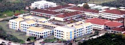 Aerial view of a campus featuring several buildings with red roofs and green spaces. - Olive Oil Times